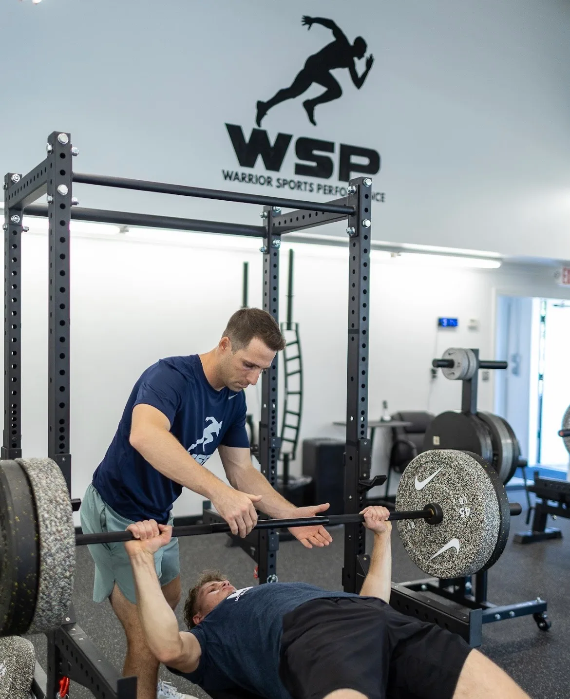Coach spotting an athlete during a barbell bench press at WSP