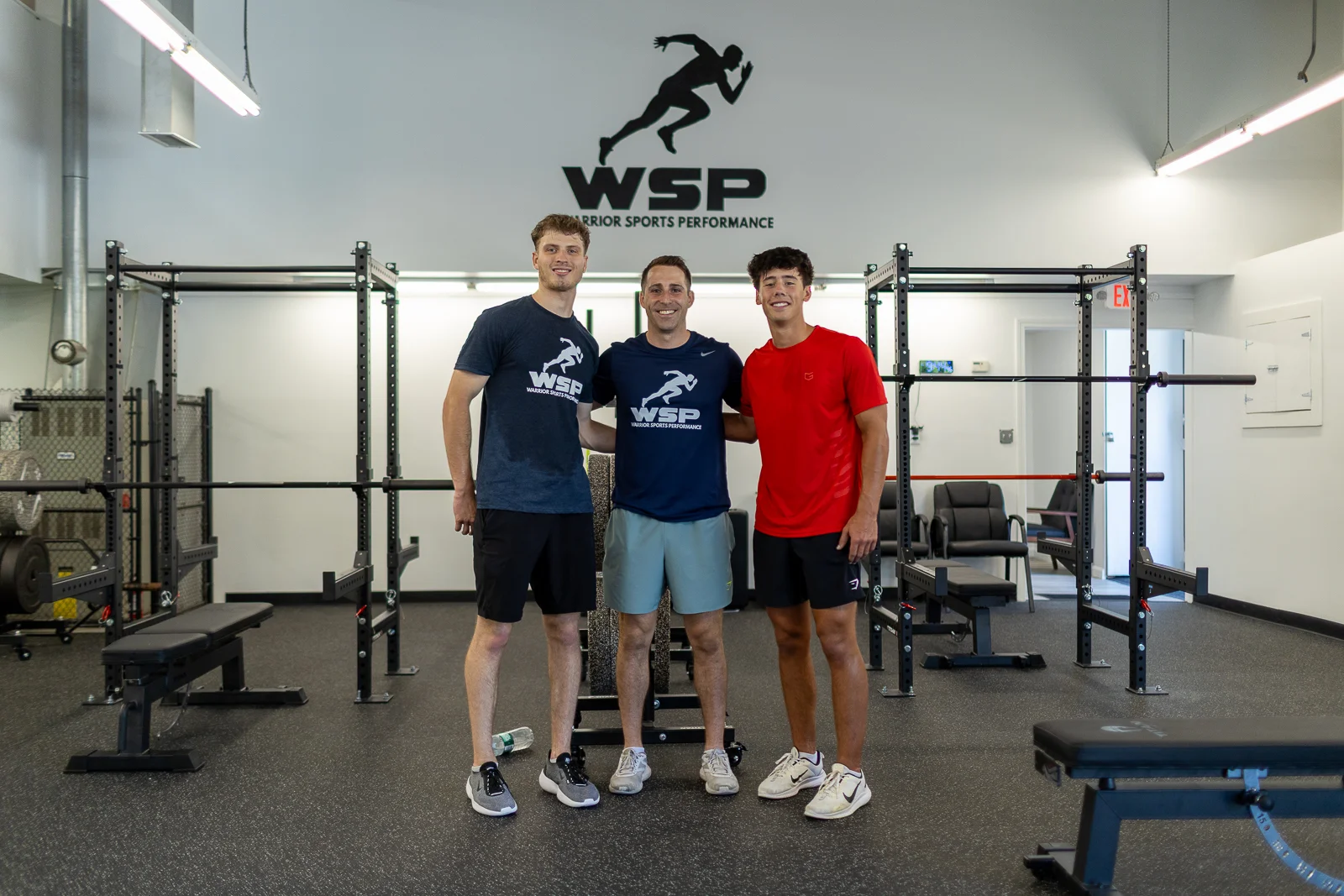Coach Ben with two athletes beneath the WSP logo
